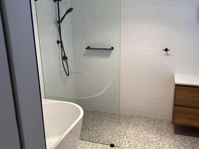 Finished bathroom with walk-in shower, freestanding bath and terrazzo-look floor