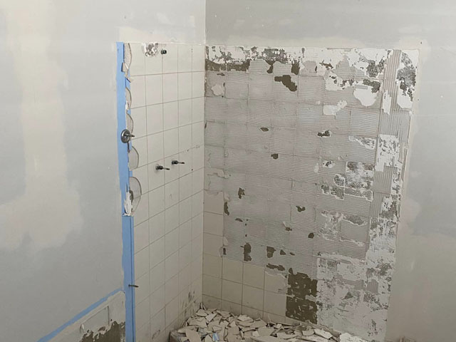 Shower during demolition: wall tiles partly stripped back
