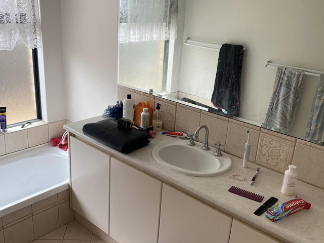 Bathroom before renovation: cluttered vanity, beige tiles and bath