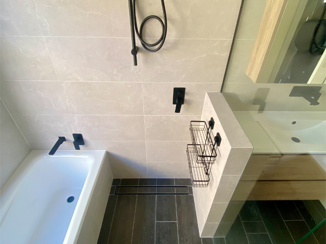 Bathroom after renovation: bath beside a walk-in shower with dark floor tiles