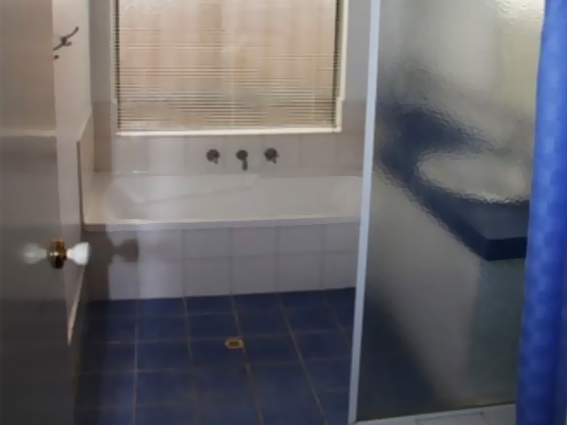 Bathroom before renovation: blue floor tiles and bath behind a shower curtain