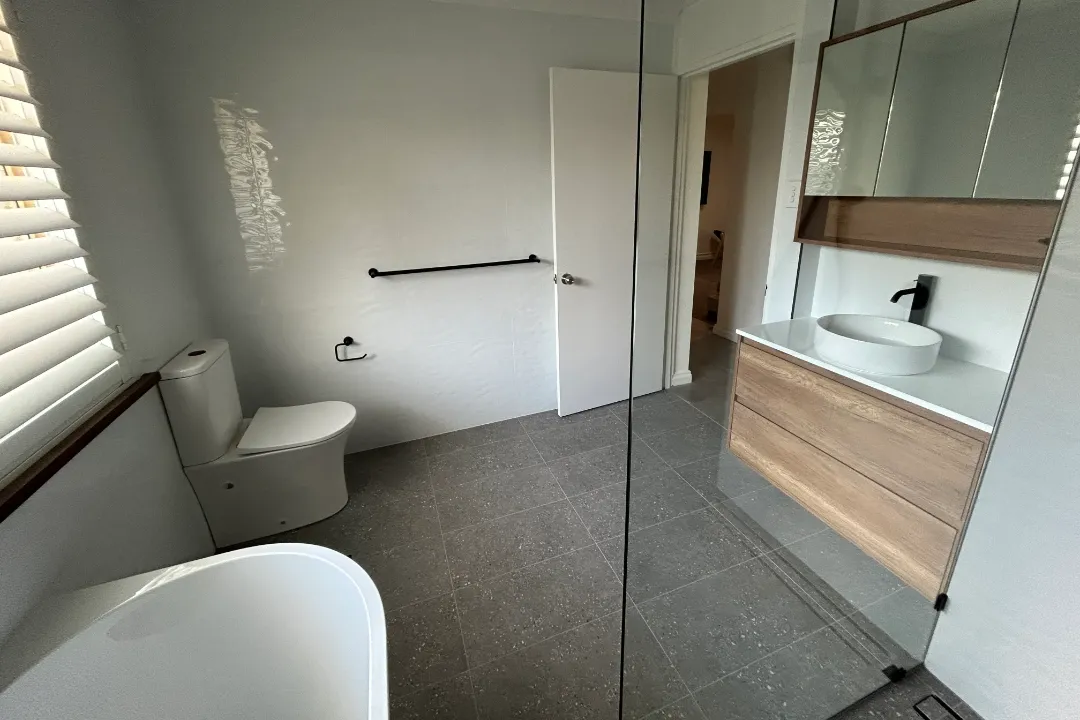 Small Bathroom Renovations Bathroom with speckled grey floor tiles, timber-look vanity and freestanding bath
