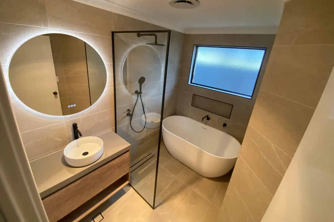 Bathroom Renovations Bayswater Bathroom with backlit oval mirror, freestanding bath and black-framed shower screen