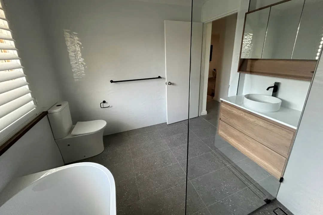 Bathroom Renovations Bayswater Bathroom with speckled grey floor tiles, timber-look vanity and freestanding bath