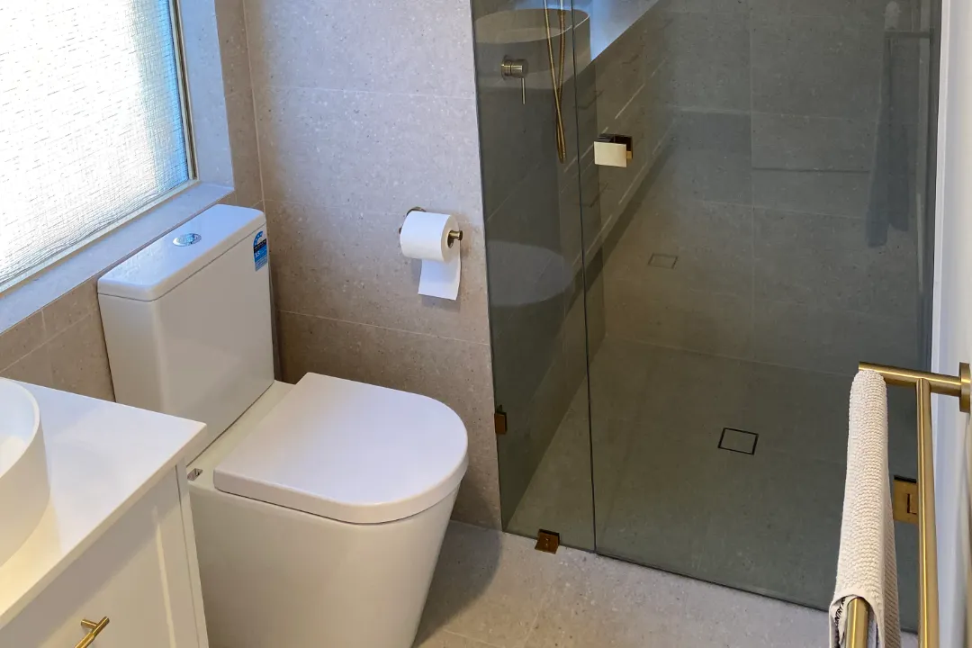 Bathroom Renovations Bayswater Toilet beside a frameless glass shower with brass fittings and towel rail