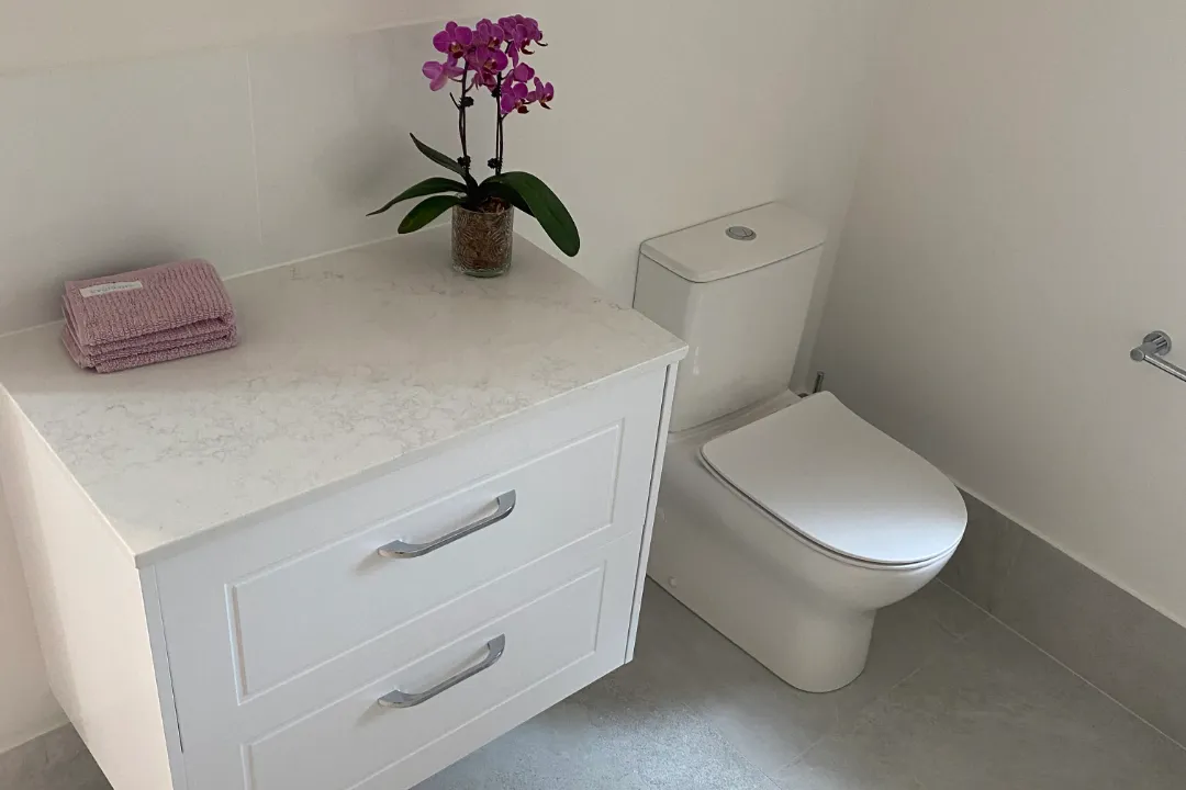 Bathroom Renovations Woodvale White wall-hung vanity with drawers and an orchid beside a toilet