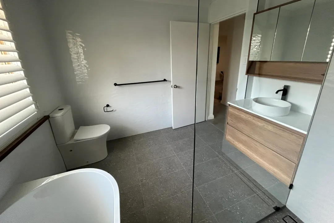 Bathroom Renovations Woodvale Bathroom with speckled grey floor tiles, timber-look vanity and freestanding bath