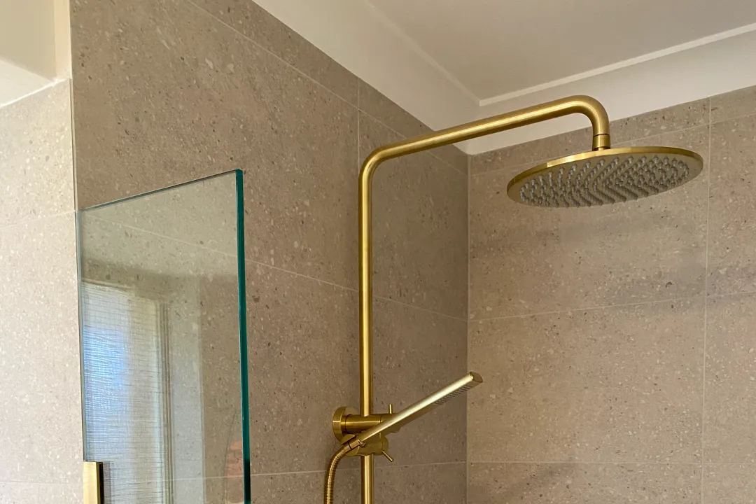 Bathroom Renovations Ellenbrook Brushed brass rain shower beside a frameless glass screen