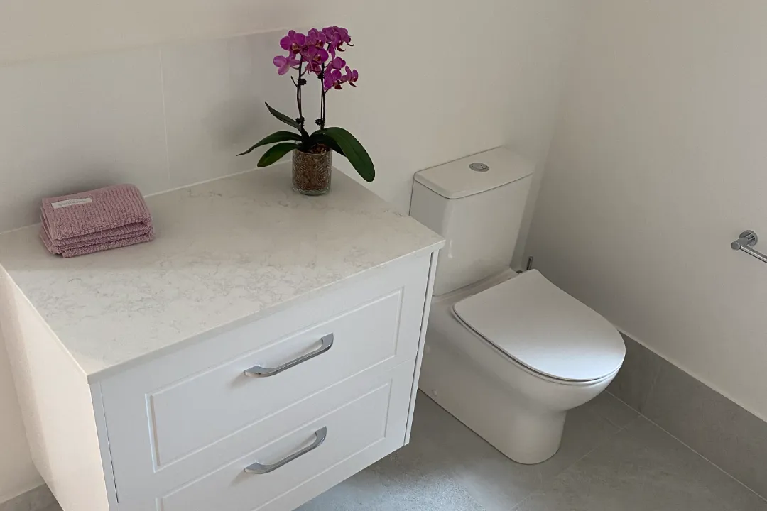 Bathroom Renovations Ellenbrook White wall-hung vanity with drawers and an orchid beside a toilet
