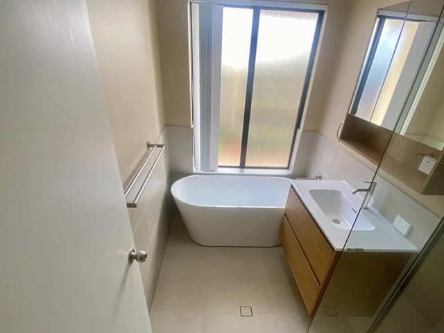 Same bathroom after renovation: freestanding bath and timber-look vanity