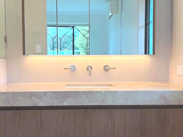 Bathroom after renovation: stone benchtop, wall-mounted tapware and mirror cabinet