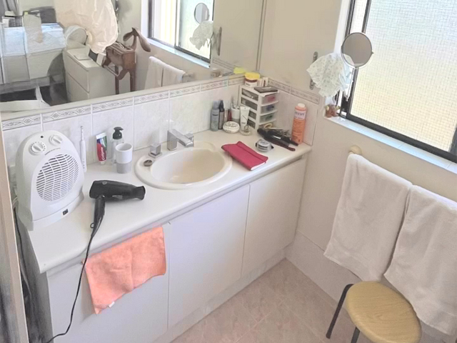 Bathroom before renovation: long white vanity with tiled splashback and mirror
